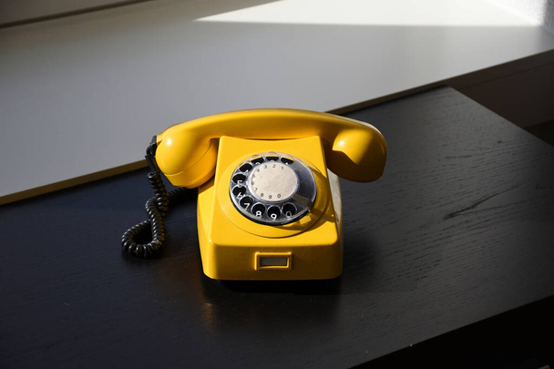 Stary Retro Vintage żółty telefon obrotowy na czarnym drewnianym stole - Zdjęcie, obraz