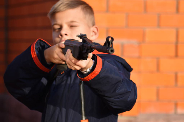 Boy shoots gun. Teenager with gun. Child is learning to shoot  - Φωτογραφία, εικόνα