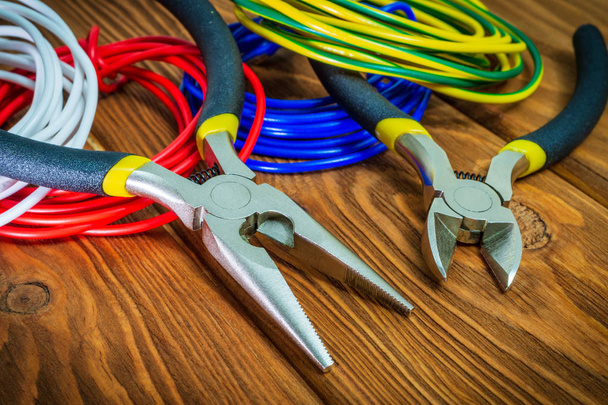 Alicates ferramenta e fios para eletricista closeup em placas de madeira
 - Foto, Imagem