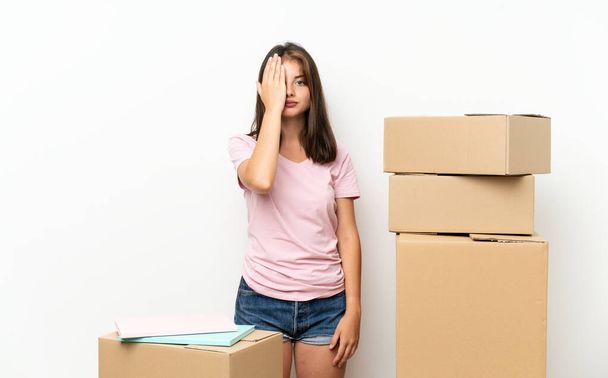 Giovane ragazza che si muove in una nuova casa tra scatole che coprono un occhio a mano
 - Foto, immagini