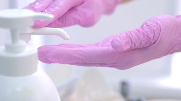 Doctor woman squeezes gel from dispenser on hands in gloves, closeup view. - Filmagem, Vídeo