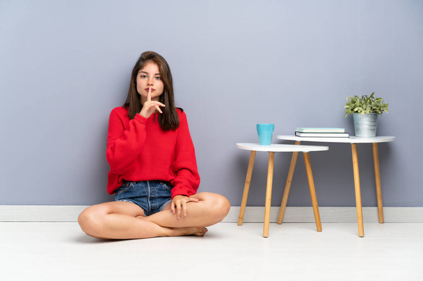 Fiatal nő ül a padlón csinál csend gesztus - Fotó, kép