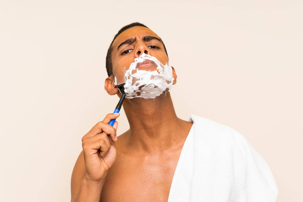 Young handsome man shaving his beard over isolated background - Photo, Image