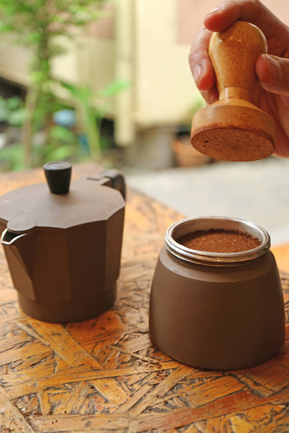 Ruka člověka drží manipulaci s kohoutkem mletou kávu pro plochý povrch před vařením v hrnci - Fotografie, Obrázek