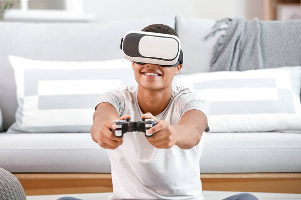 Afrikkalainen-amerikkalainen teini poika virtuaalitodellisuus lasit pelaa videopelejä kotona
 - Valokuva, kuva