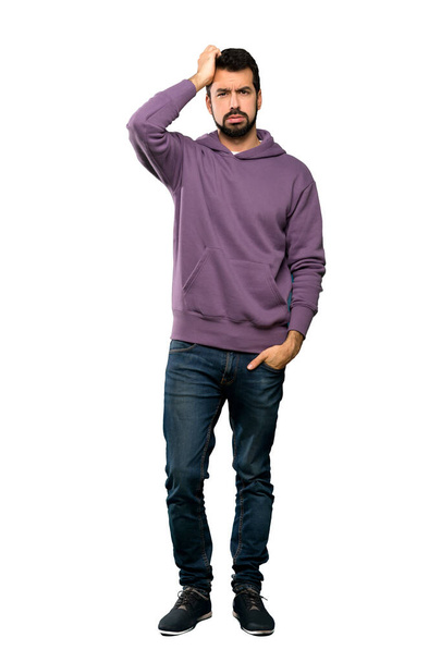 Full-length shot van Handsome man met sweatshirt met een uitdrukking van frustratie en niet begrijpen over geïsoleerde witte achtergrond - Foto, afbeelding