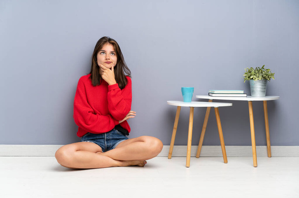 Young woman sitting on the floor thinking an idea - Photo, Image