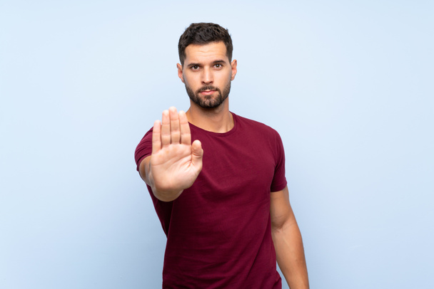 Handsome man over isolated blue background making stop gesture - Photo, Image