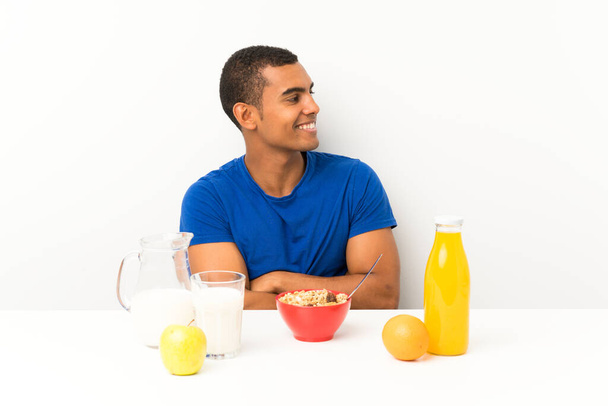 Young man having breakfast in a table looking to the side - Photo, Image