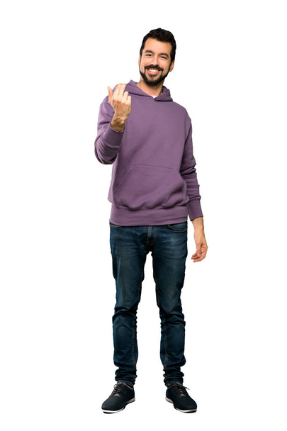 Full-length shot of Handsome man with sweatshirt inviting to come with hand. Happy that you came over isolated white background - Фото, зображення