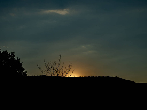 Sonnenuntergang hinter Hügeln und Büschen - Foto, Bild