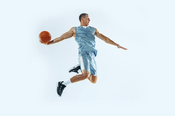 Young caucasian basketball player against white studio background - 写真・画像