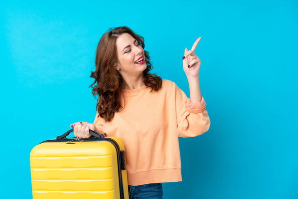 Matkustaja nainen matkalaukku yli eristetty sininen tausta osoittaa etusormella loistava idea
 - Valokuva, kuva