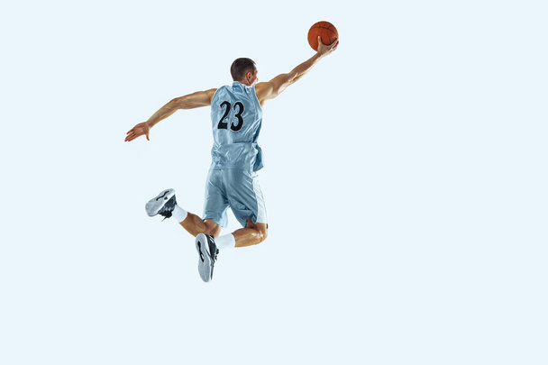 Young caucasian basketball player against white studio background - Foto, afbeelding