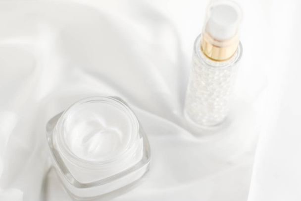 Face cream moisturizer jar and serum gel on white silk, skin car - 写真・画像