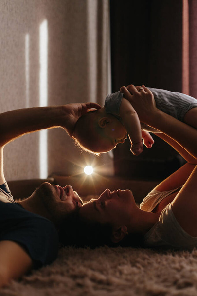 Baby with his parents playing on the bed. Happy family at home. Lifestyle cozy photos. Little boy 4 months old - Photo, Image