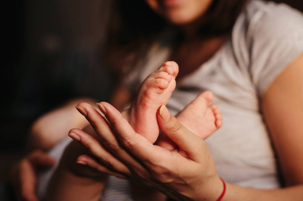 母の手で赤ちゃんの足。女性形に小さな新生児の足の手のクローズ アップ。ママと彼女の子供。幸せな家族の概念。マタニティの美しいイメージ - 写真・画像
