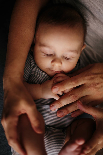 Close up portrait of sleeping baby covered by parents hands - Фото, зображення