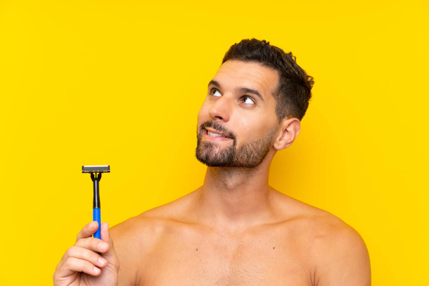 Homem barbeando sua barba olhando para cima enquanto sorri
 - Foto, Imagem