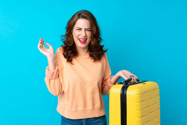 Mujer viajero con maleta sobre fondo azul aislado riendo
 - Foto, imagen