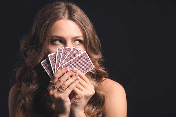 Beautiful young woman with playing cards on dark background - Fotoğraf, Görsel