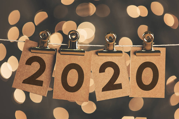 2020 new year sign pegged to a string with bokeh lights in the background - Foto, Imagem