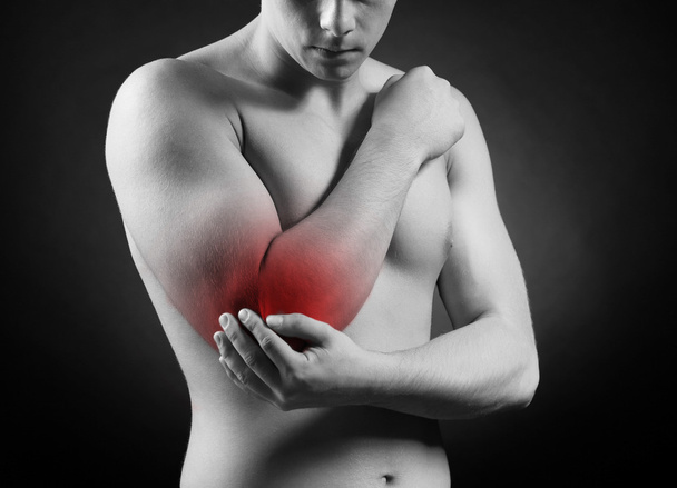 jonge man met elleboog pijn, op rode achtergrond - Foto, afbeelding