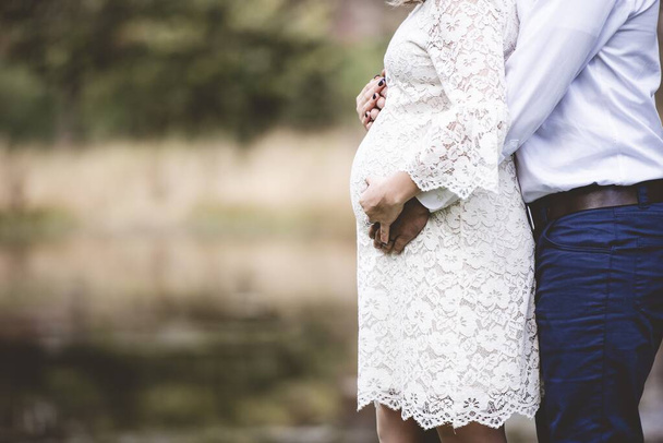 Closeup shot of a pregnant couple with their hands on the belly and a blurred background - Photo, image