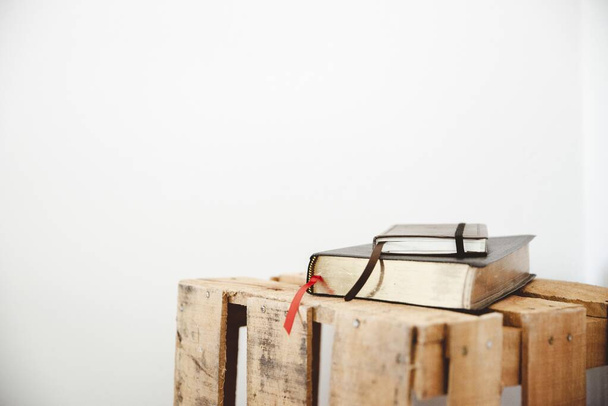 Closeup shot of a bible and notepad on a wooden box with a white background - Zdjęcie, obraz
