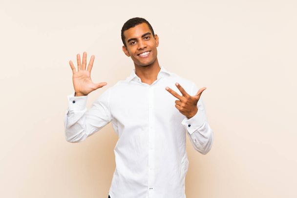 Νεαρός όμορφος μελαχρινός άντρας πάνω από απομονωμένο φόντο μετρώντας οκτώ με δάχτυλα - Φωτογραφία, εικόνα