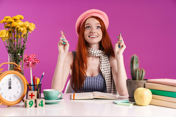 Image of happy teenage girl keeping fingers crossed while studyi - Foto, Bild