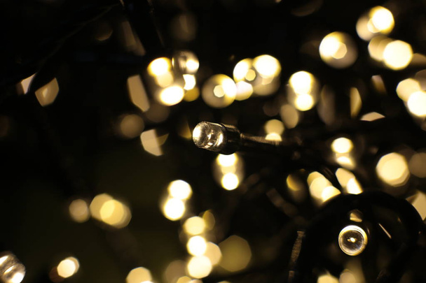 Defocused lights of warm shade, festive background. Christmas garland out of focus. - Photo, Image