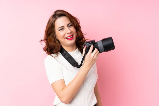 junge Russin vor isoliertem rosa Hintergrund mit professioneller Kamera - Foto, Bild