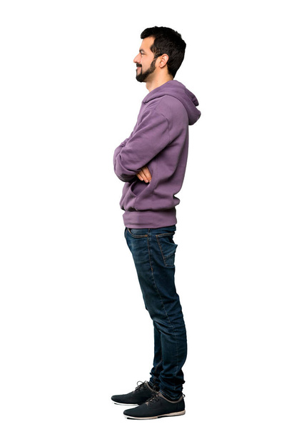 Ganzkörperaufnahme eines gutaussehenden Mannes mit Sweatshirt in seitlicher Position über isoliertem weißem Hintergrund - Foto, Bild