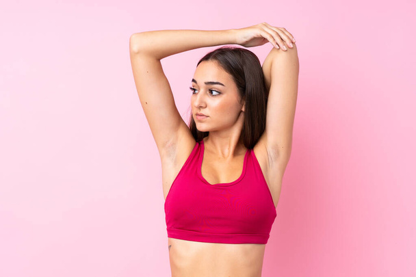 Joven deporte chica sobre aislado rosa fondo estiramiento - Foto, imagen