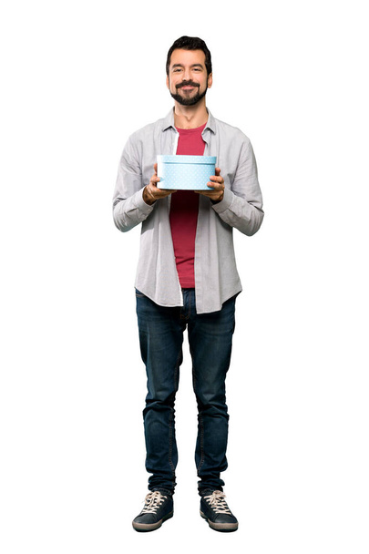 Celovečerní snímek pohledný muž s plnovousem drží dar nad izolované bílým pozadím - Fotografie, Obrázek