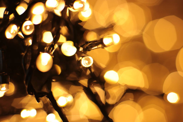 Defocused lights of warm shade, festive background. Christmas garland out of focus. - Foto, Bild