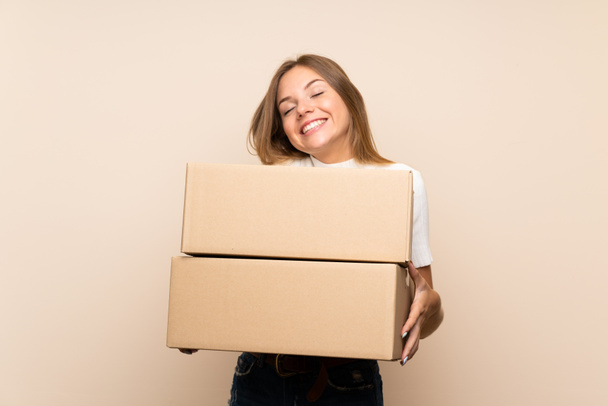 junge blonde Frau mit isoliertem Hintergrund hält eine Schachtel, um sie an einen anderen Ort zu verschieben - Foto, Bild