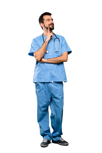Tiro completo de Cirurgião médico homem pensando uma ideia ao olhar para cima sobre fundo branco isolado
 - Foto, Imagem