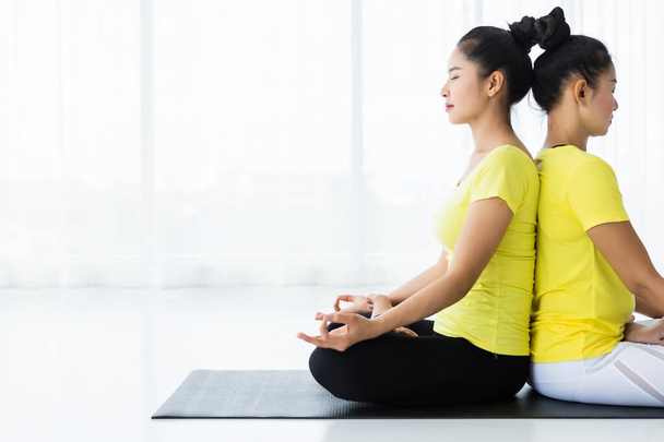 Deux jeunes femmes asiatiques s'entraînent à pratiquer le yoga en robe jaune ou
 - Photo, image