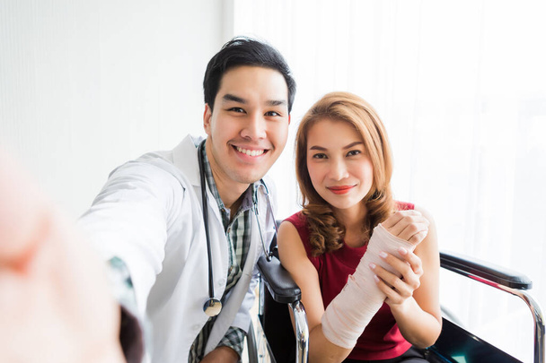 Selfie of smiling man doctor with a female patient wear arm spli - Fotoğraf, Görsel
