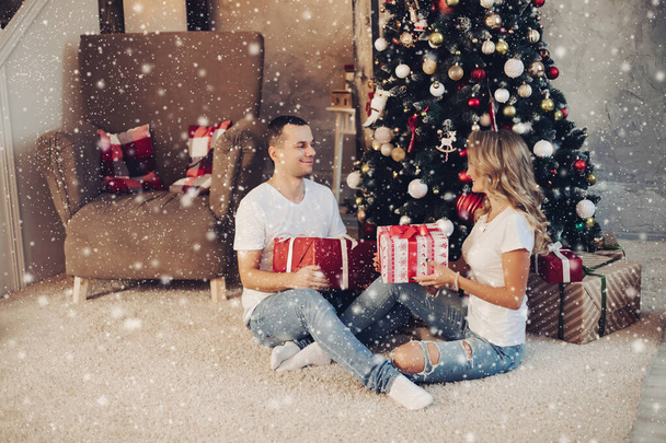 Αγαπημένο ζευγάρι με δώρα απέναντι στο χριστουγεννιάτικο δέντρο. - Φωτογραφία, εικόνα