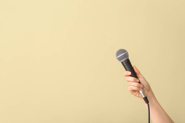 Mano femenina con micrófono sobre fondo de color
 - Foto, imagen
