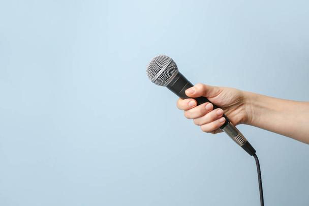 weibliche Hand mit Mikrofon auf farbigem Hintergrund - Foto, Bild