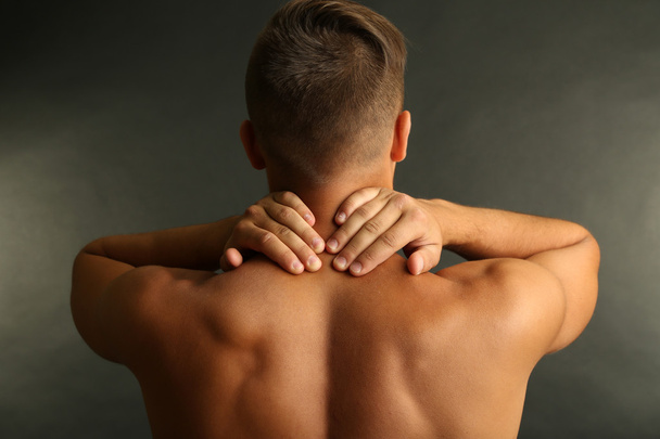 Young man with neck pain on grey background - Photo, Image
