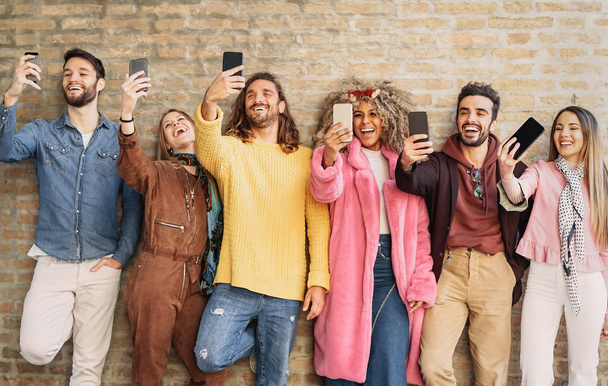 Happy group friends taking selfie with mobile phone outdoor - Young trendy people having fun with new mobile smartphone apps for social media - Youth culture millennial generation and Technology concept - Fotografie, Obrázek