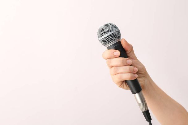 Female hand with microphone on light background - Zdjęcie, obraz