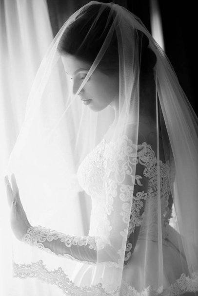 monochrome portrait of caucasian beautiful attractive woman bride in traditional european white dress  - Фото, изображение