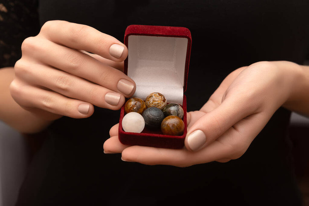 Sets of round stones in female hands on black background - Photo, image