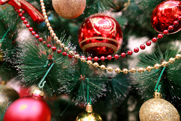 Πρωτοχρονιάτικα πολύχρωμα διακοσμητικά στολίδια σε χριστουγεννιάτικο δέντρο. Δωμάτιο διακοσμημένο με χριστουγεννιάτικη γιορτή, σκηνή διακοπών με διάφορα σχήματα, πολύχρωμες μπάλες, διακοσμητικά τόξα λάμψη και πουλί στο δέντρο. - Φωτογραφία, εικόνα